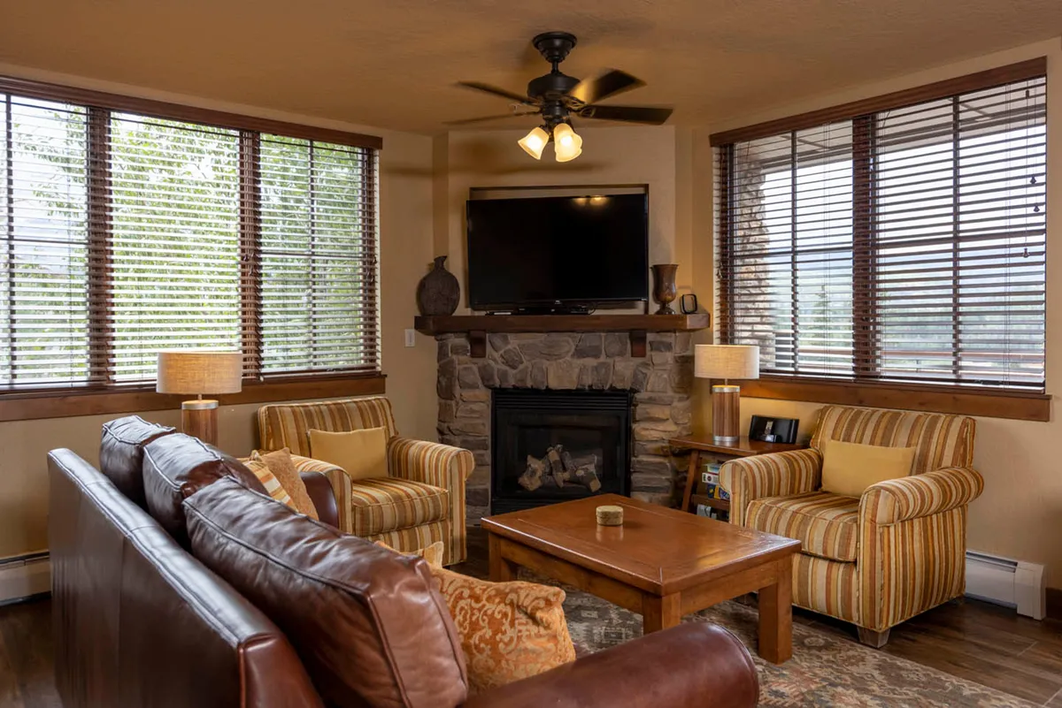A warm, inviting living room with a glowing fireplace, soft seating arranged for socializing or watching the mounted flat-screen TV, and a central coffee table ideal for games or shared snacks. The space exudes comfort and is ideal for family movie nights or après-ski relaxation.