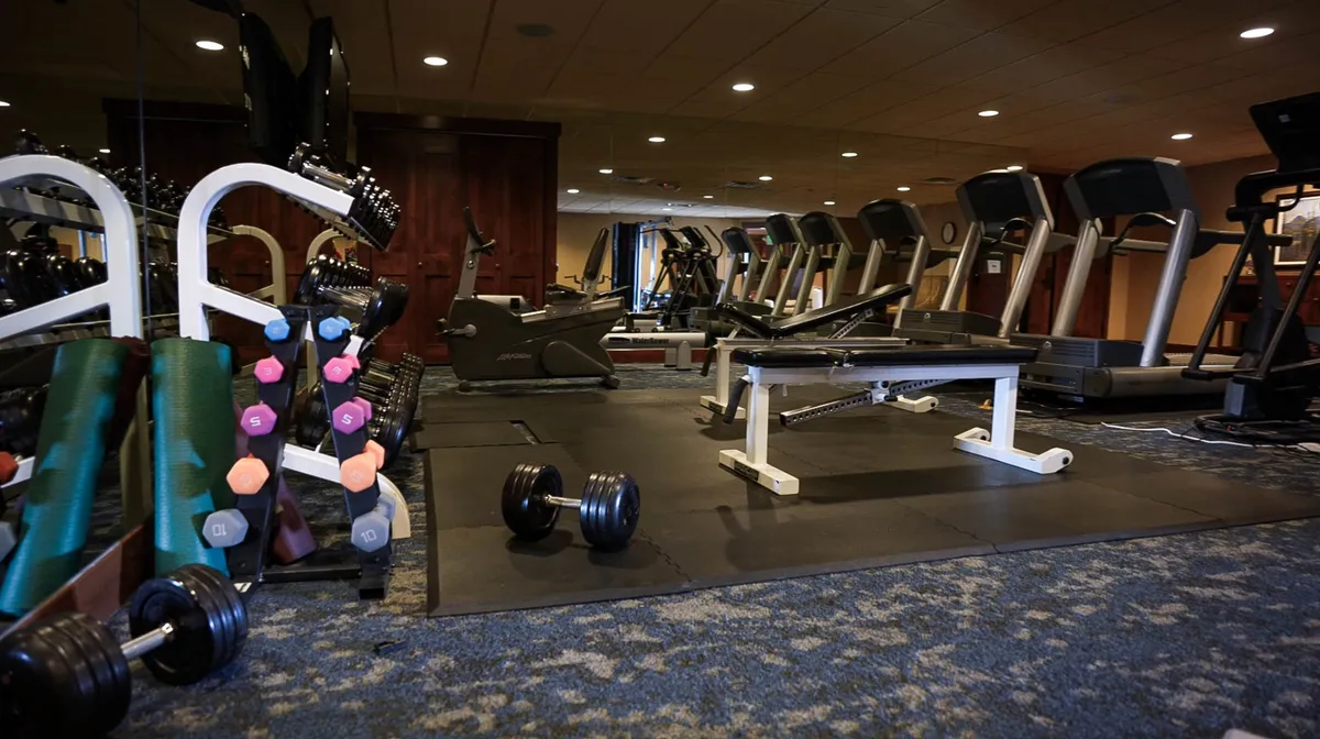 A well-equipped fitness center with dumbbells, treadmills, and other exercise equipment arranged in a bright, energetic space. The setting encourages both individual workouts and group fitness sessions, appealing to families who value health and activity during their stay.