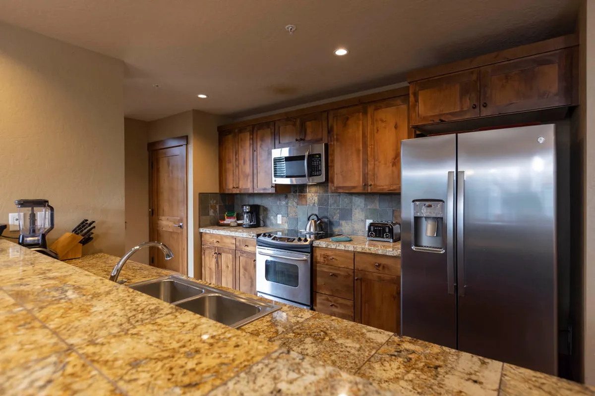 This image focuses on a well-appointed kitchen featuring warm wood cabinetry, gleaming granite countertops, a sizable sink, and premium stainless steel appliances. The thoughtful layout and upscale finishes create an inviting environment for cooking and entertaining.